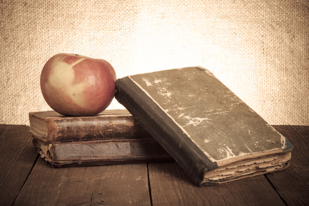 Still life with apple and a stack of old books on old wooden table. Tonedの写真素材