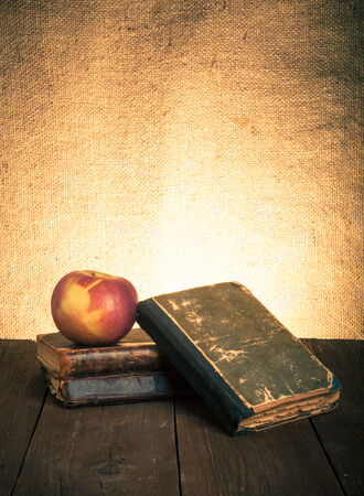 Still life with apple and a stack of old books on old wooden table. Tonedの写真素材