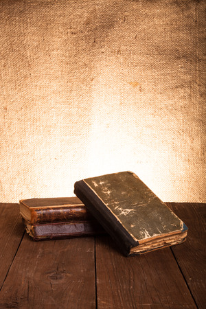 A stack of old books on old wooden table against the background of burlap.の写真素材