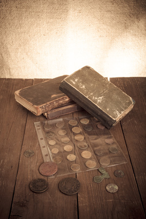 Vintage books and coins on old wooden table. Toned.の写真素材