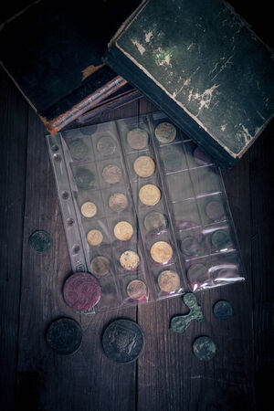 Vintage books and coins on old wooden table. Toned.の写真素材