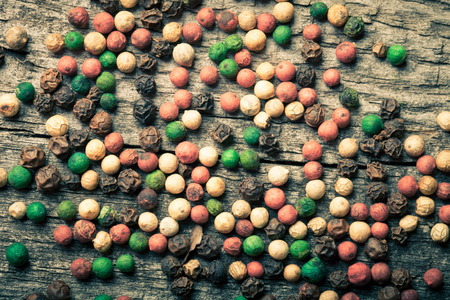 Colorful peppercorns on an old wooden table. Toned.の写真素材