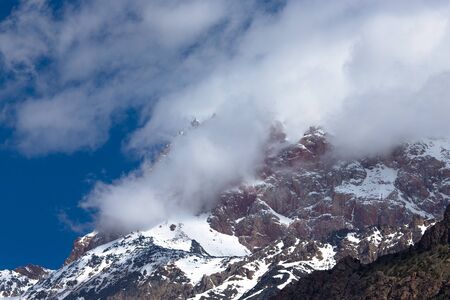 Clouds lie on the snow-covered tops of the rocks. Landscape.の写真素材