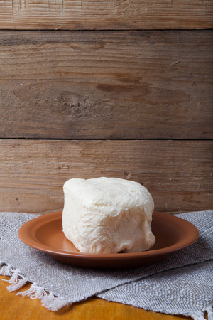 Large piece of butter on plate on linen napkin. Rustic still life. Wooden background.の写真素材
