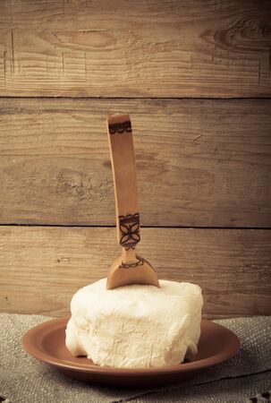 Large piece of butter with spoon on plate on linen napkin. Rustic still life. Wooden background. Toned.の写真素材