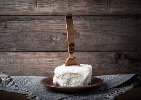Large piece of butter with spoon on plate on linen napkin. Rustic still life. Wooden background. Toned.の写真素材