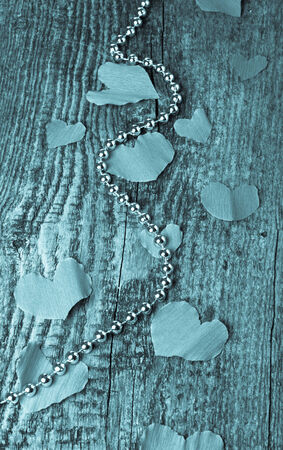 Many Valentine hearts and shiny beads on the old wooden table. Toned.の写真素材