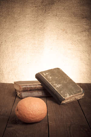 Still life with orange and a stack of old books on old wooden table. Tonedの写真素材
