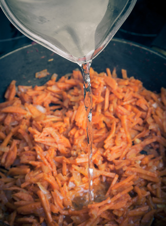 Frying pan with fried carrots. Water flowing. Toned.の写真素材
