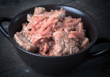 Fish marinated with carrots in a brown ceramic bowl on old wooden table. Toned.の写真素材