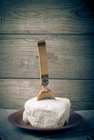 Large piece of butter with spoon on plate on linen napkin. Rustic still life. Wooden background. Toned.の写真素材
