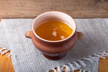 Clay pot with ghee on linen napkin. Rustic still life. Wooden background.の写真素材