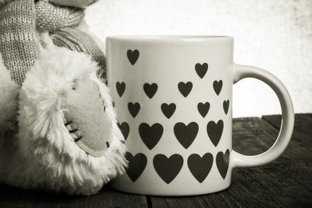 Paw of Teddy bear  and mug with hearts on the old wooden table. Toned.の写真素材