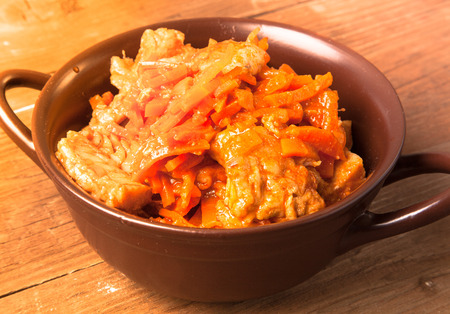 Fish marinated with carrots in a brown ceramic bowl on old wooden table. Toned.の写真素材