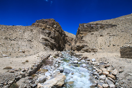 Tajikistan. Mountain stream flowing down the canyon with the barren peaks of the Pamirsの写真素材