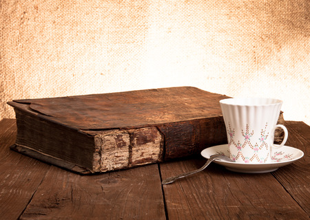 Cup of coffee, old books on the old wooden table.の写真素材
