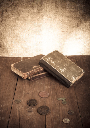 Vintage books and coins and spectacles on old wooden table. Tonedの写真素材