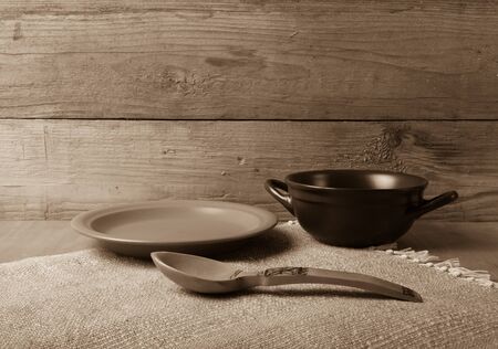 Rustic still life. Bowl, spoon and plate on linen napkin. Wooden background. Toned.の写真素材