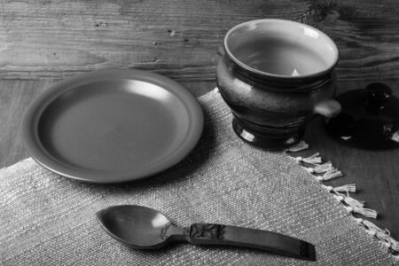 Rustic still life. Clay pot, spoon and plate on linen napkin. Wooden background. Toned.の写真素材