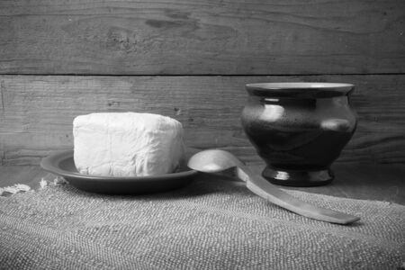 Butter on plate, clay pot and spoon on linen napkin. Rustic still life. Wooden background. Toned.の写真素材