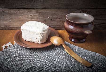 Butter on plate, clay pot and spoon on linen napkin. Rustic still life. Wooden background. Toned.の写真素材