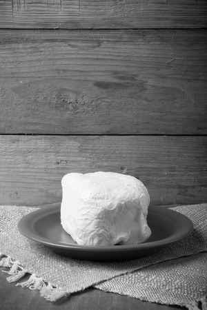 Large piece of butter on plate on linen napkin. Rustic still life. Wooden background. Toned.の写真素材