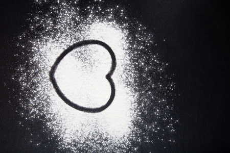 Shape of heart drawn on the flour on a black background.の写真素材