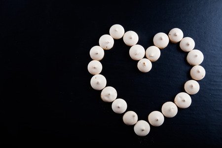 Small cookies laid in the shape of heart on black background.の写真素材