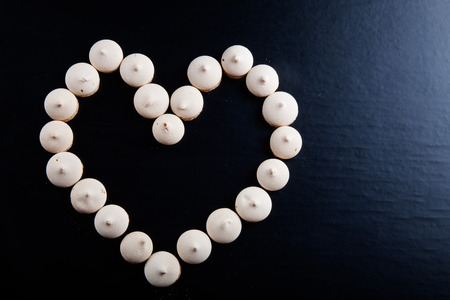 Small cookies laid in the shape of heart on black background.の写真素材