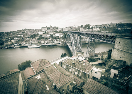Red tiled roofs, metal bridge, old houses and the river Douro in Porto. Low clouds. Toned.の写真素材