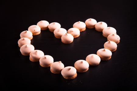 Small cookies laid in the shape of heart on black background. Toned.の写真素材