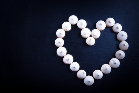Small cookies laid in the shape of heart on black background. Toned.の写真素材