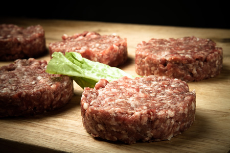 Raw cutlet of minced meat on a wooden cutting board. Toned.の写真素材