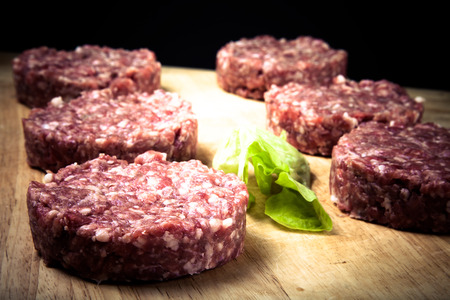 Raw cutlet of minced meat on a wooden cutting board. Toned.の写真素材