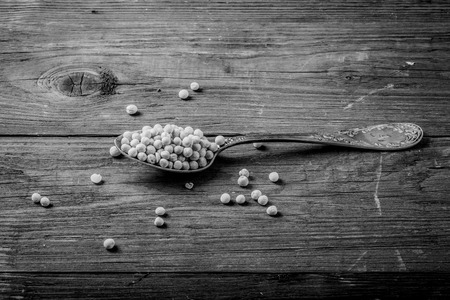 silver spoon with dried peas on old wooden table.の写真素材