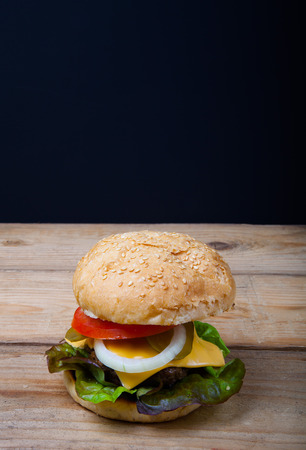 Homemade grilled hamburger on wooden table with black background.の写真素材