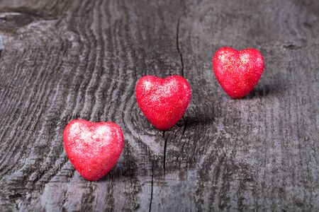 Three shiny red hearts on old wooden background.の写真素材