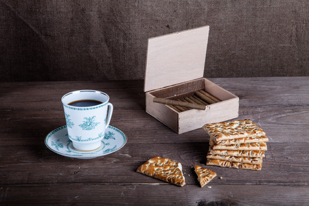 Cup of coffee, biscuits and a box of cigarettes on old wooden table.の写真素材
