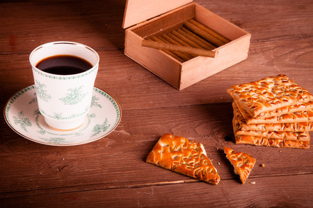 Cup of coffee, biscuits and a box of cigarettes on old wooden table. Toned.の写真素材
