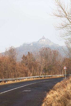 Paved country road in autumn. Clear blue sky and house on the hill.の写真素材