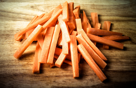 A bunch of pieces of carrots on a wooden cutting board. Toned.の写真素材