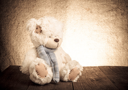 Teddy bear is sitting on the old wooden table. Toned.の写真素材