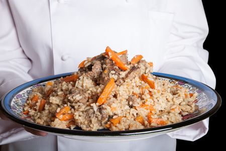 Turkish dish with pilaf in the hands of the cook.