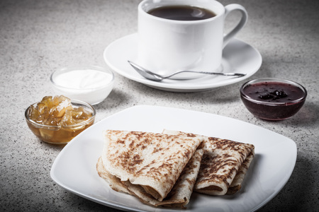 Cup of tea with jam, sour cream and russian pancakes - blini. Toned.の写真素材