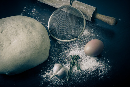 Flour, rolling pin, egg, rosemary, garlic and dough for pie. Toned.の写真素材