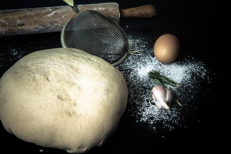 Flour, rolling pin, egg, rosemary, garlic and dough for pie. Toned.の写真素材