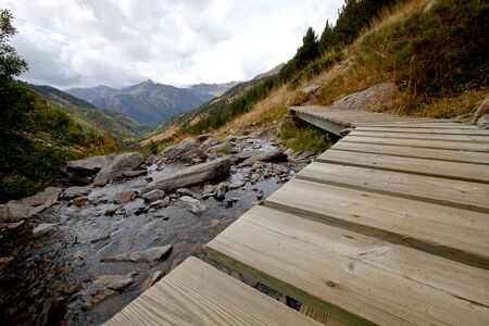 Wood flooring over a mountain river. Mountain, forest, clouds, dry grass.の写真素材