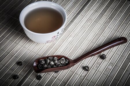 cup of green tea and tea leaves spoon on a napkin from a bambooの写真素材