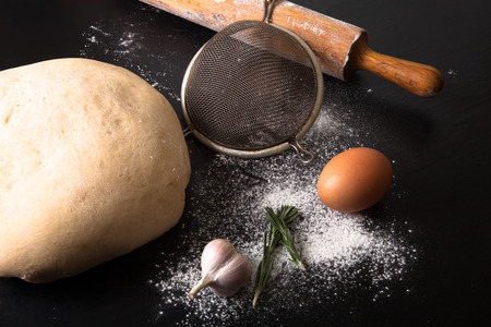 Flour, rolling pin, egg, rosemary, garlic and dough for pie.の写真素材