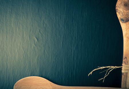 Two wooden spoons on the edges of the black background. Space for text. Toned.の写真素材